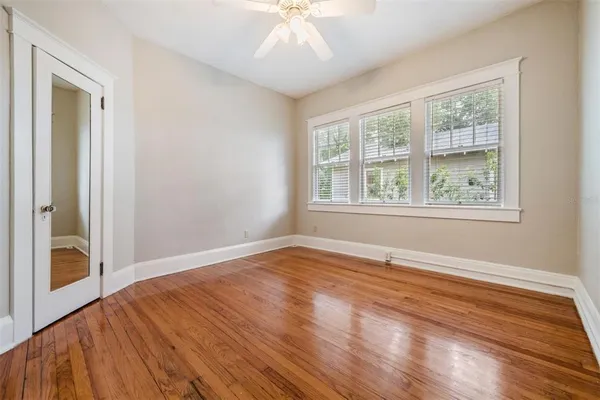 a view of an empty room with wooden floor and a window