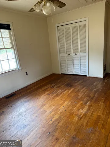 an empty room with wooden floor closet and windows