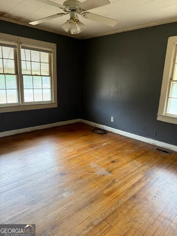 an empty room with wooden floor and windows
