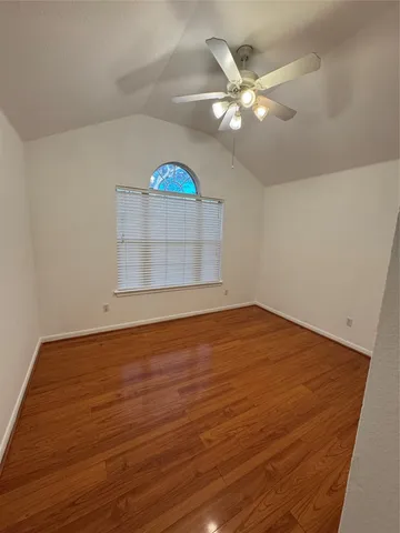 an empty room with wooden floor and chandelier fan