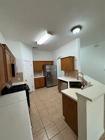 a large kitchen with stainless steel appliances a stove a sink and a refrigerator