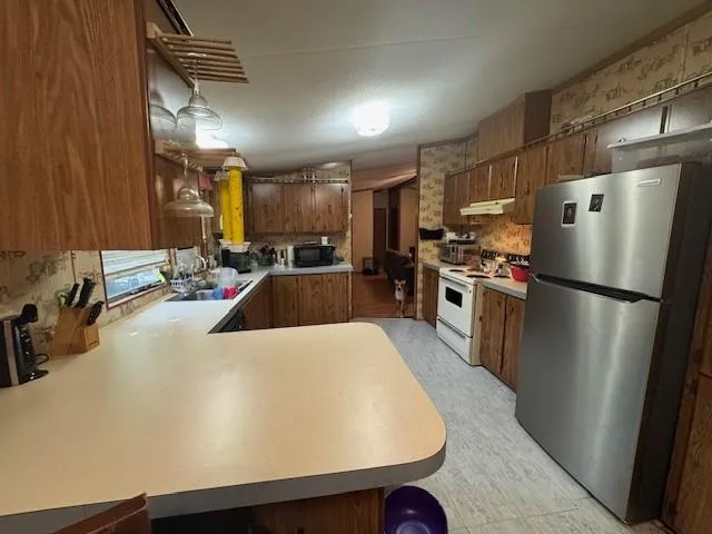 a kitchen with kitchen island a counter top space a sink a refrigerator and a stove