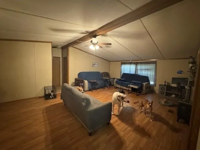 a living room with furniture a flat screen tv and a wooden floor