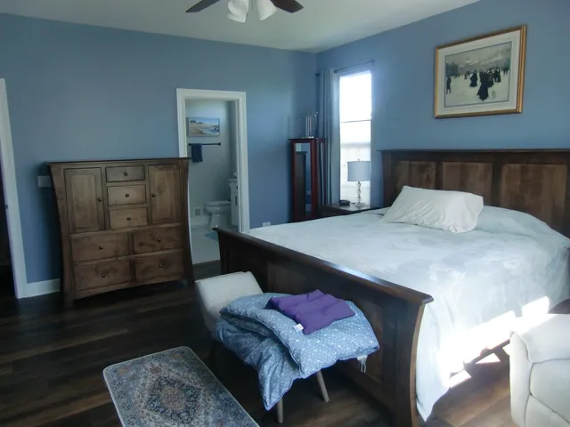 a bedroom with a bed a dresser and next to a window