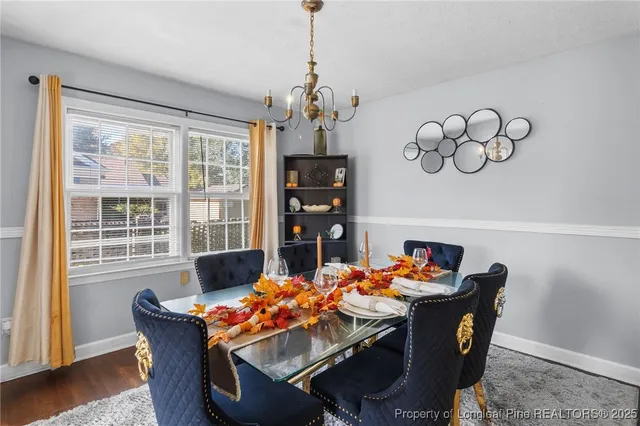 a dining room with furniture wooden floor a chandelier and a painting