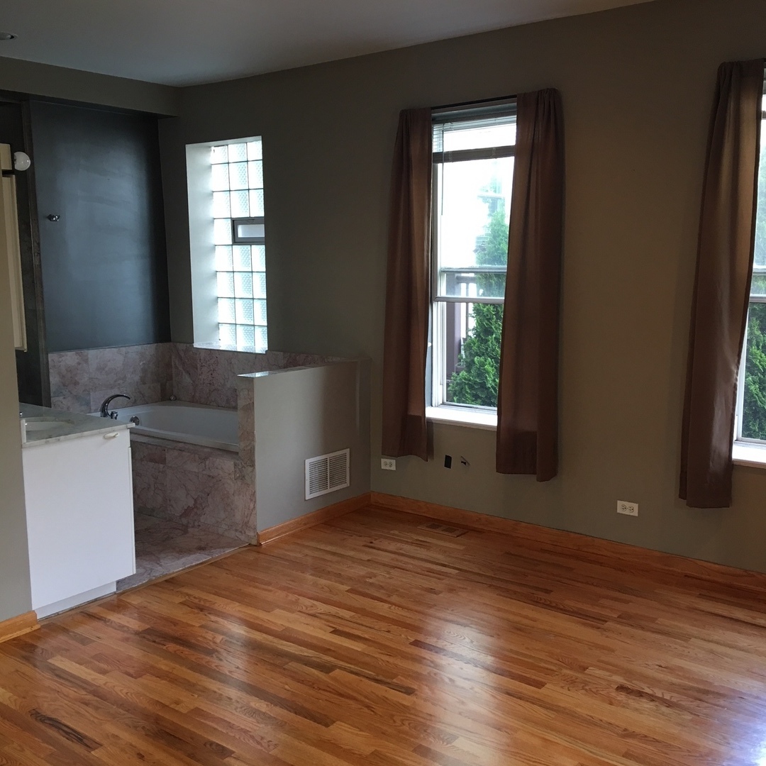 1915 West Huron Street, Unit 2 Chicago, IL 60622 - Photo 17 of 23 an empty room with wooden floor and windows