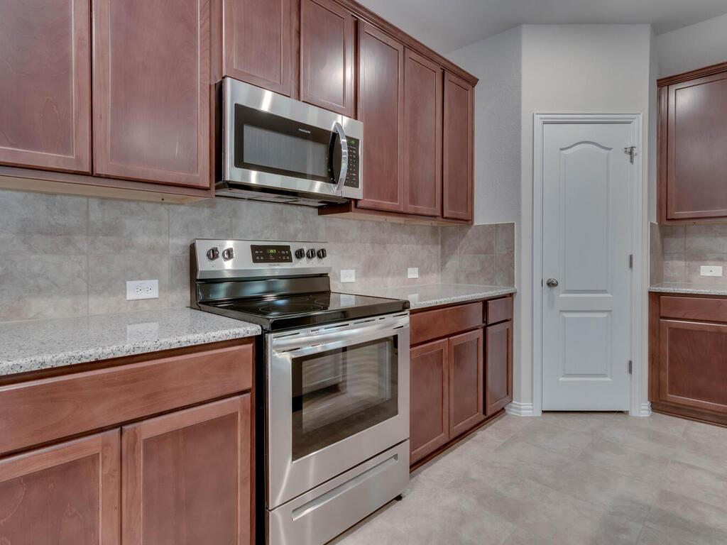1104 Ridge Runner Drive Georgetown, TX 78628 - Photo 3 of 27 a kitchen with stainless steel appliances granite countertop a stove microwave and refrigerator