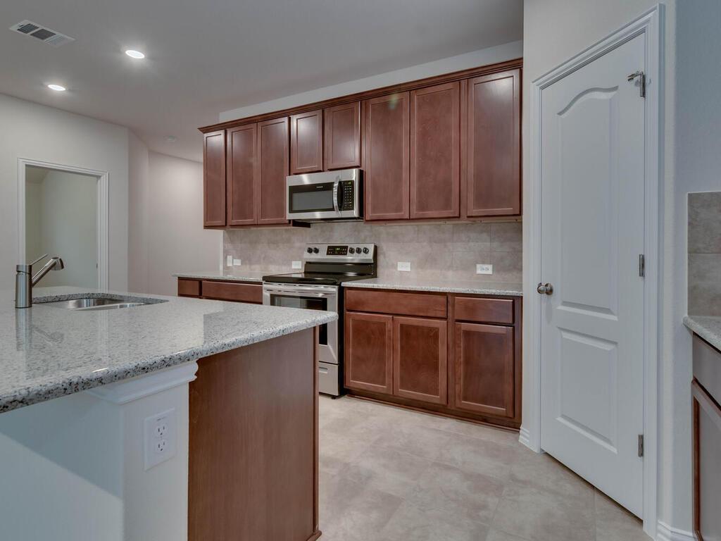 1104 Ridge Runner Drive Georgetown, TX 78628 - Photo 4 of 27 a kitchen with stainless steel appliances granite countertop a sink stove microwave and refrigerator