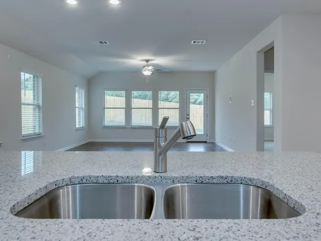 a kitchen with a sink granite counter tops and a window