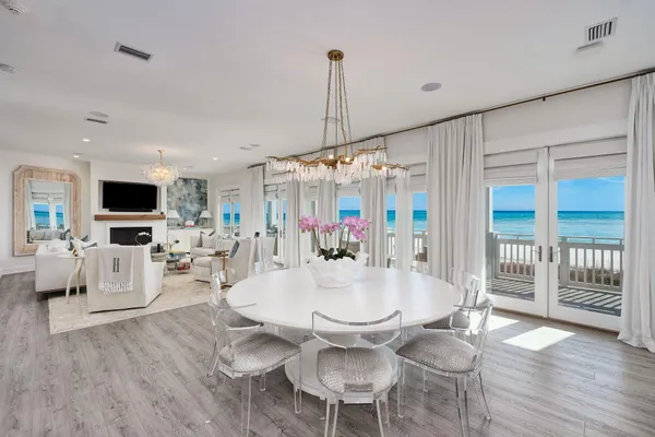 a dining room with wooden floor a chandelier a glass table and chairs