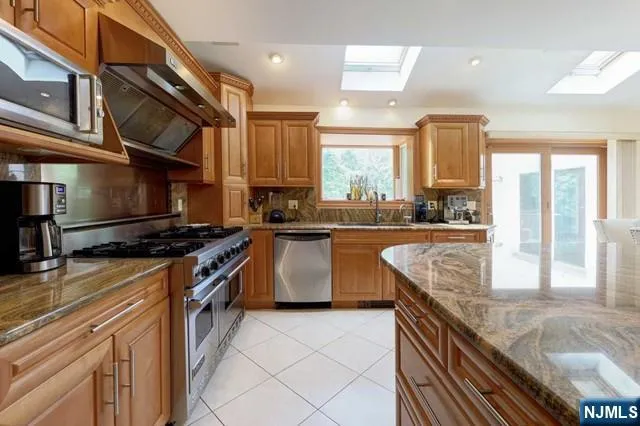 a kitchen with stainless steel appliances granite countertop a sink a stove and a refrigerator