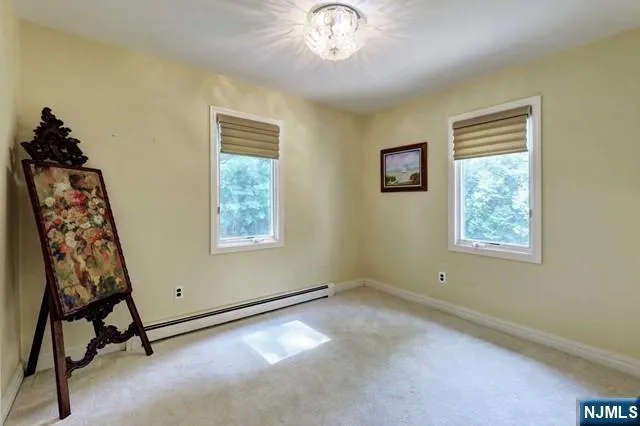 a view of an empty room with window and chandelier fan