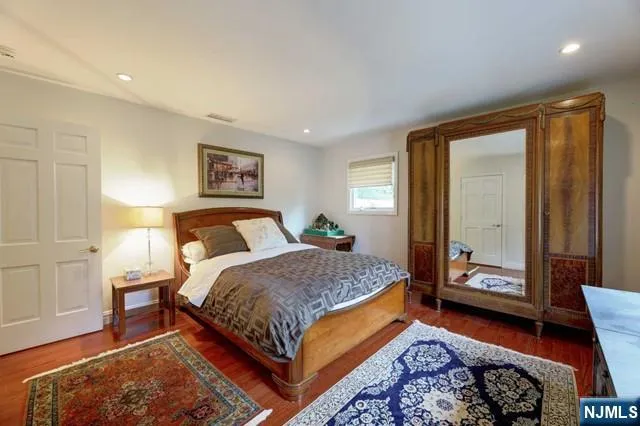 a bedroom with a bed and a dresser with wooden floor