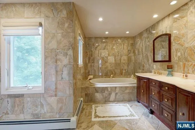 a spacious bathroom with a double vanity sink toilet mirror and bathtub