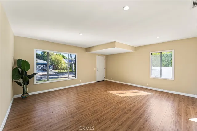 an empty room with wooden floor and windows