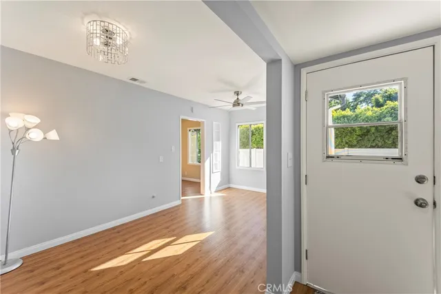 a view of an empty room with wooden floor and a window