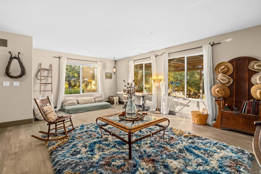 25258 Black Canyon Road Santa Ysabel, CA 92070 - Photo 20 of 69 a living room with furniture a fireplace and a table with wooden floor