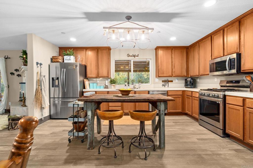 25258 Black Canyon Road Santa Ysabel, CA 92070 - Photo 23 of 69 a kitchen with stainless steel appliances kitchen island granite countertop a table chairs sink refrigerator and cabinets