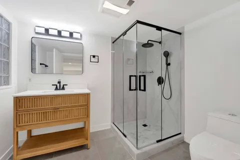 a bathroom with a shower sink mirror and toilet