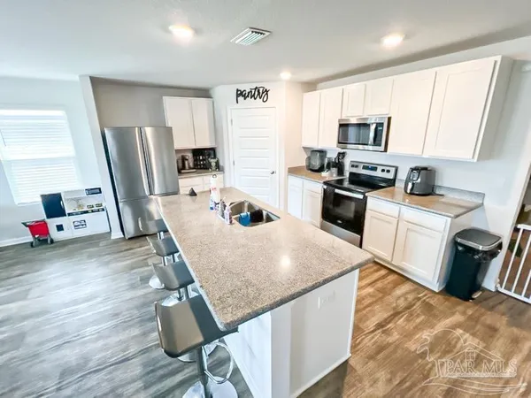 a kitchen with kitchen island a stove a sink a refrigerator a counter top space and cabinets