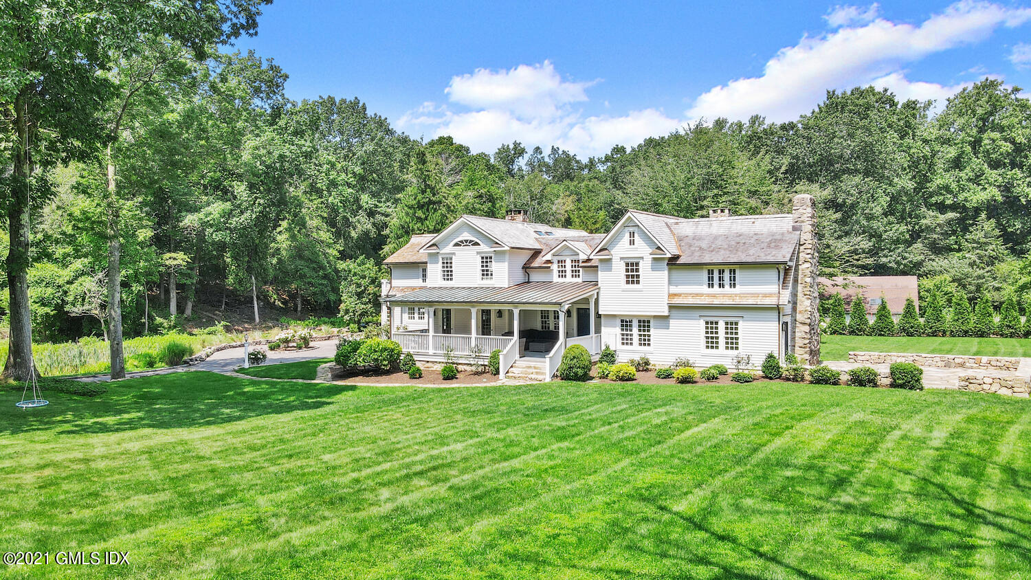 175 Cat Rock Road Cos Cob, CT 06807 - Photo 60 of 72 a front view of a house with a garden and trees