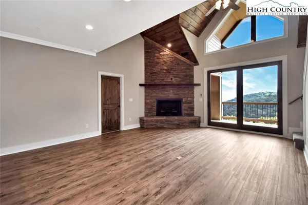 an empty room with wooden floor fireplace and windows