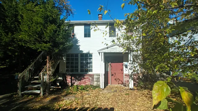 a front view of a house with a tree