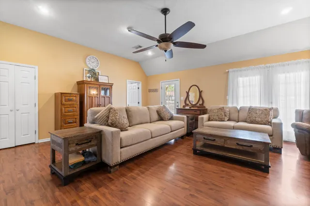 a living room with furniture a ceiling fan and a wooden floor