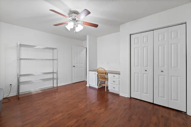 an empty room with wooden floor closet and windows
