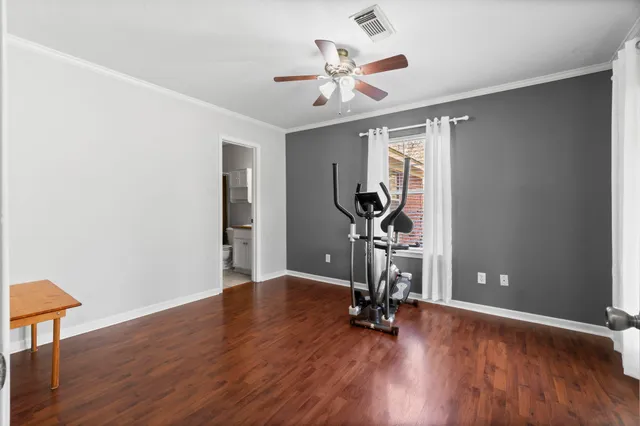 an empty room with wooden floor chandelier fan and windows