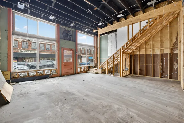 a view of an empty room with wooden floor and stairs