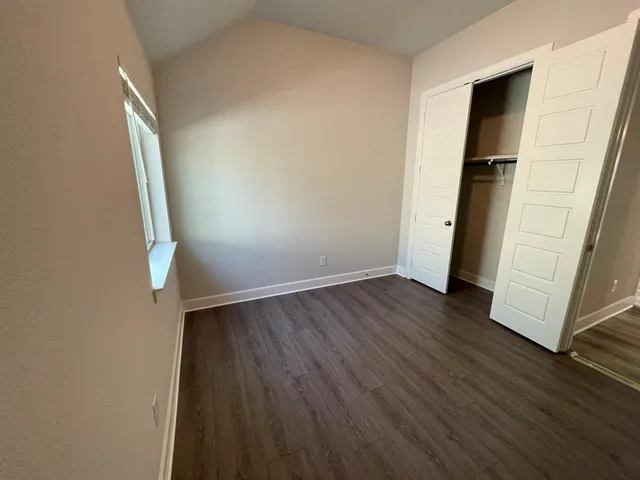 an empty room with wooden floor and entrance