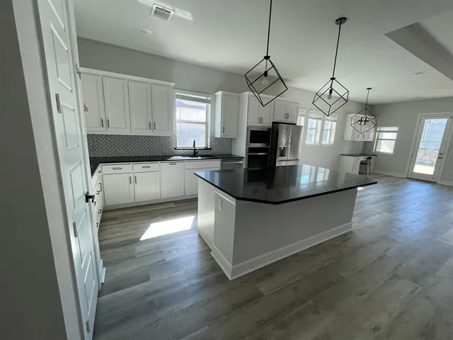 a kitchen with granite countertop a sink a counter space stainless steel appliances and cabinets
