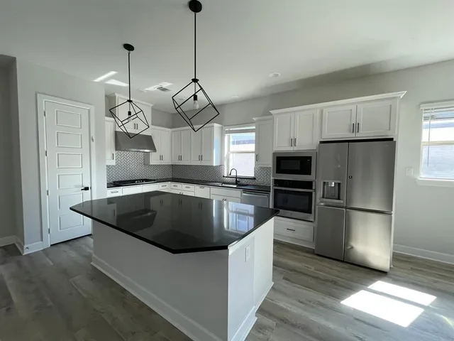a view of an empty room with wooden floor fireplace and a window
