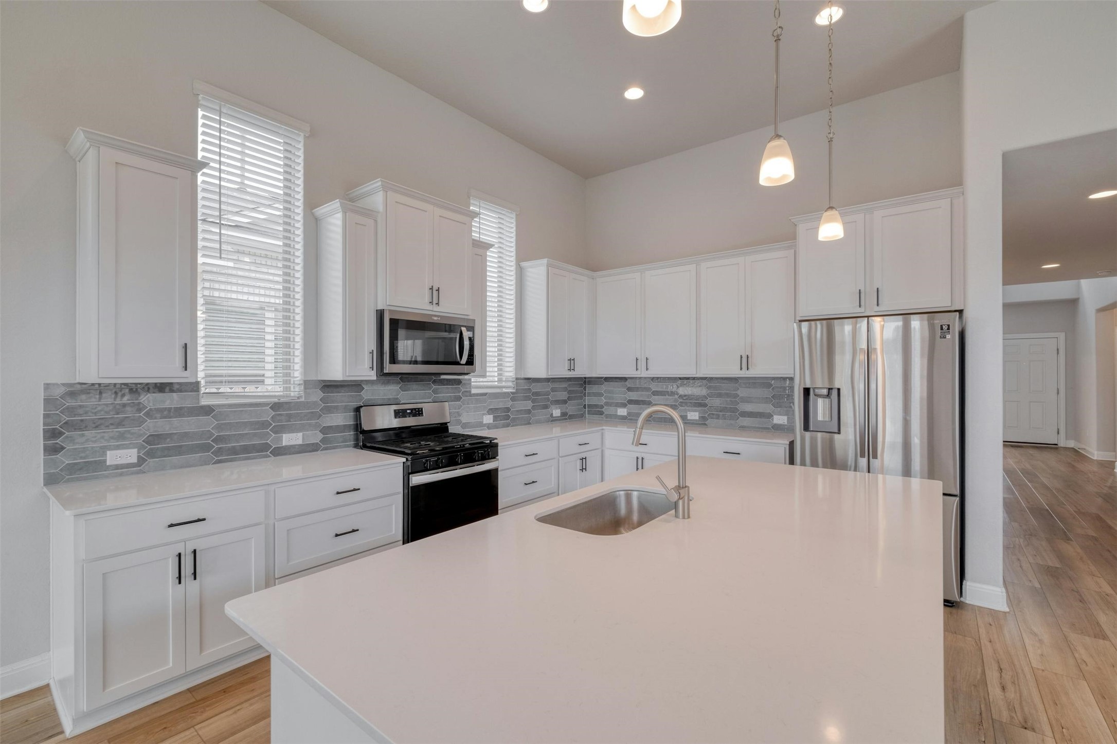 228 Rieber Road Kyle, TX 78640 - Photo 3 of 27 a kitchen with stainless steel appliances granite countertop a stove a sink a refrigerator white cabinets and a refrigerator with wooden floor