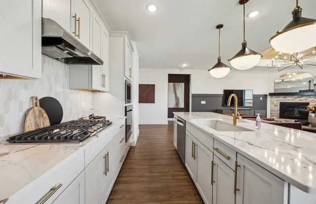 a large kitchen with stainless steel appliances kitchen island a large stove a sink dishwasher and a microwave with wooden floor