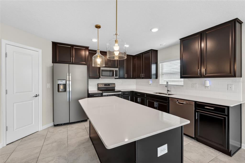 4773 Magnetite Loop Mount Dora, FL 32757 - Photo 4 of 36 a kitchen with stainless steel appliances a refrigerator sink and microwave