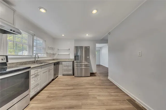 a large kitchen with stainless steel appliances lots of counter space and a sink