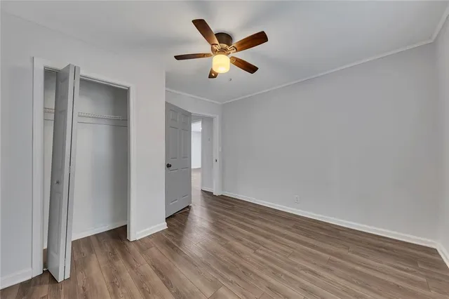 an empty room with wooden floor and ceiling fan
