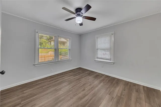 a view of an empty room with window and wooden floor