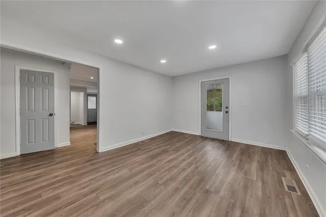 an empty room with wooden floor and windows