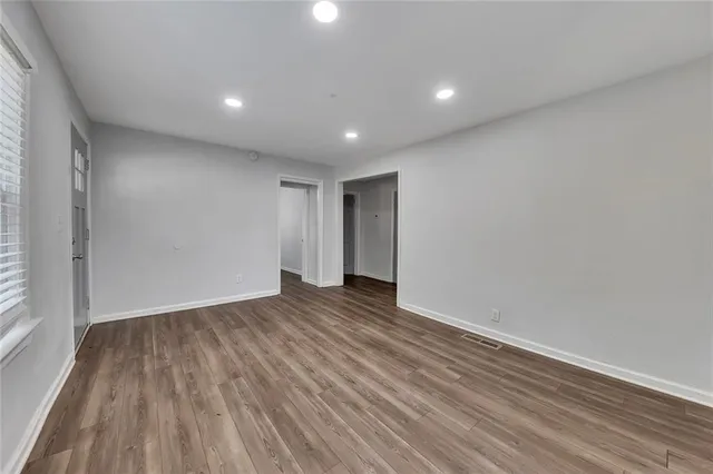 a view of an empty room with wooden floor and a window