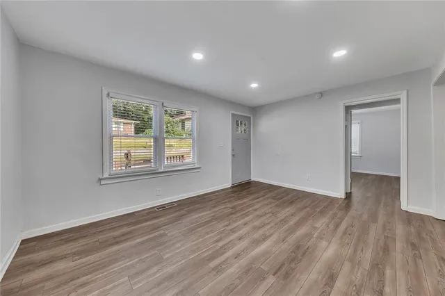 a view of an empty room with wooden floor and a window