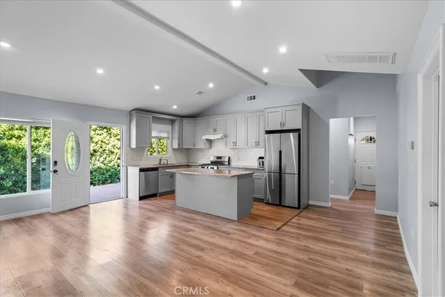 a kitchen with stainless steel appliances kitchen island granite countertop a refrigerator and a sink