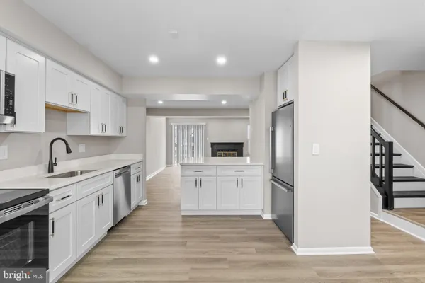 a large kitchen with stainless steel appliances kitchen island a sink dishwasher a refrigerator and a stove with wooden floors