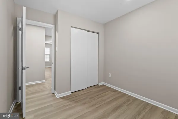 a view of an empty room with wooden floor and closet