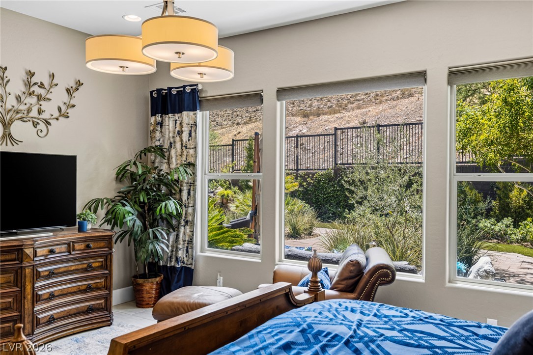 10167 Copper Edge Road Las Vegas, NV 89148 - Photo 17 of 45 Panoramic window views frame a verdant outdoor landscape in this well-appointed bedroom.