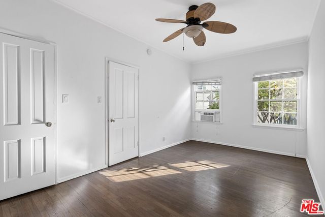 an empty room with wooden floor chandelier fan and windows