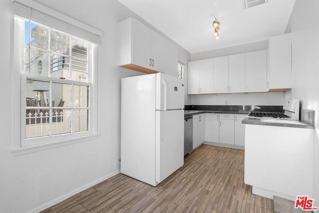 a kitchen with granite countertop a refrigerator cabinets and wooden floor