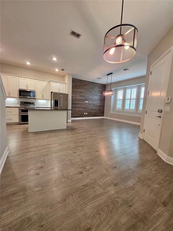 8582 Powder Ridge Trail Windermere, FL 34786 - Photo 6 of 50 an open kitchen with kitchen island stainless steel appliances a stove cabinets and wooden floor